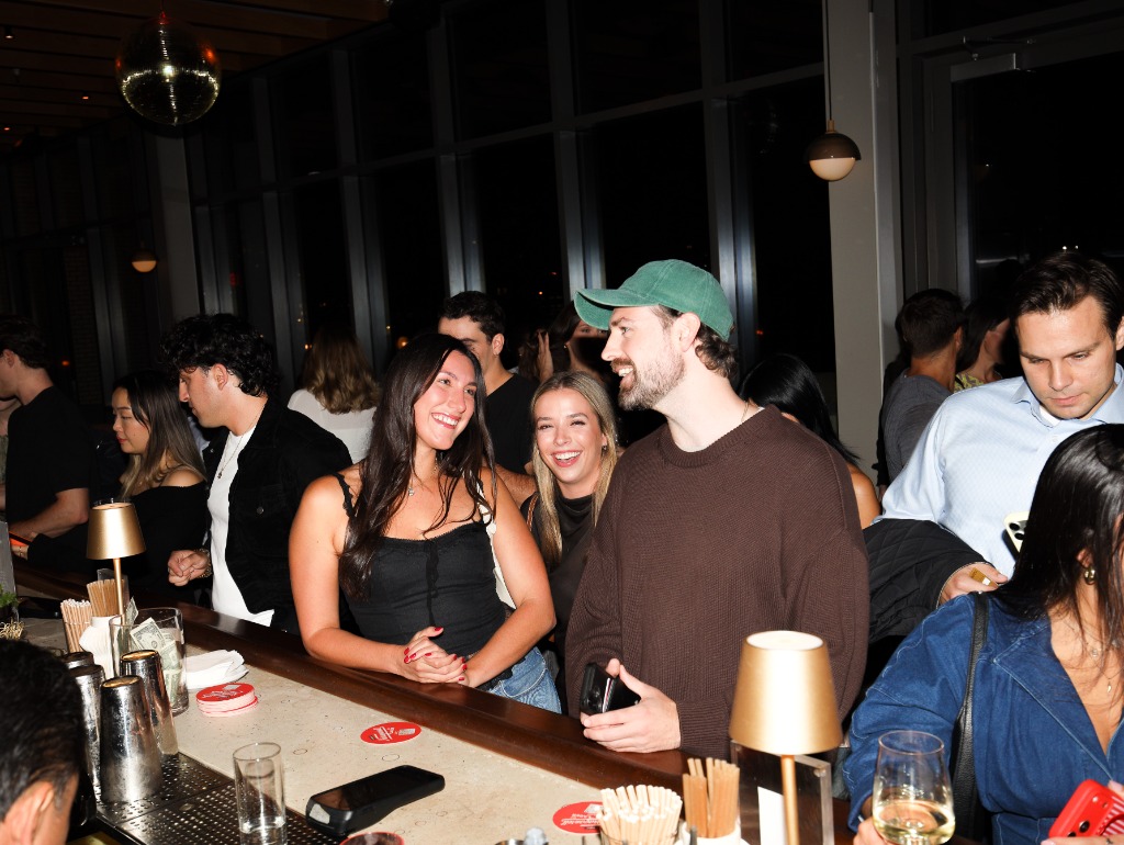 Guests smiling and talking at illuminated bar counter