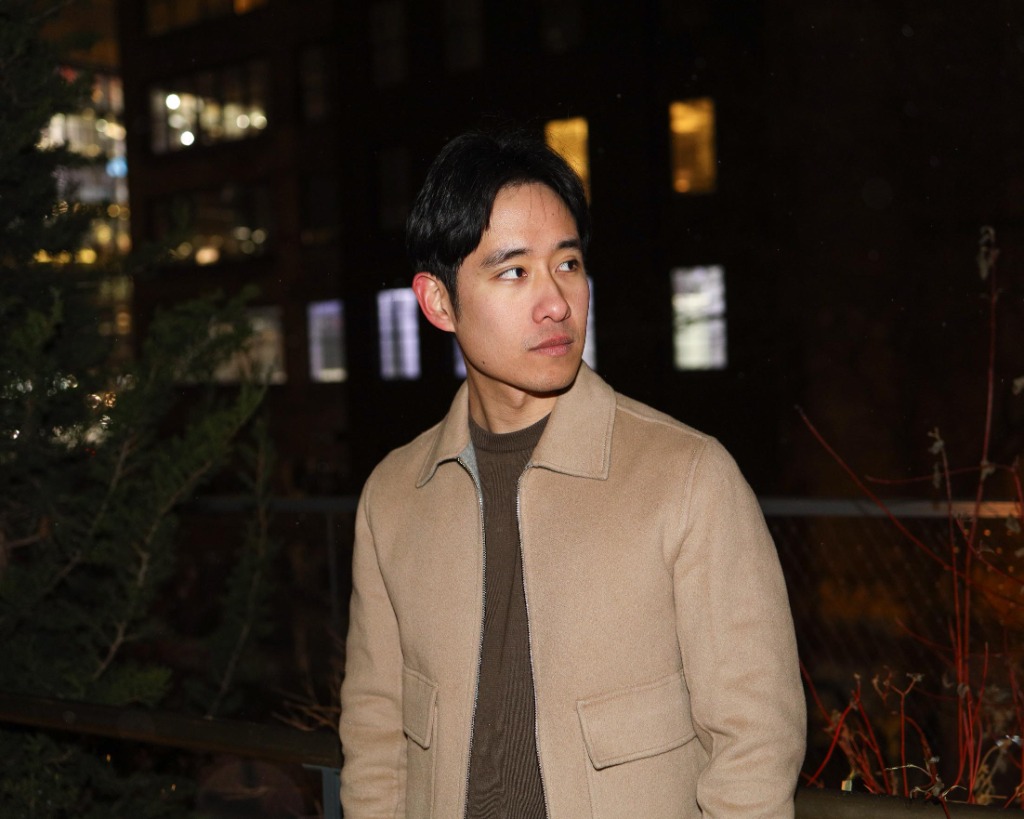 Man in tan jacket in evening city portrait with glowing background lights